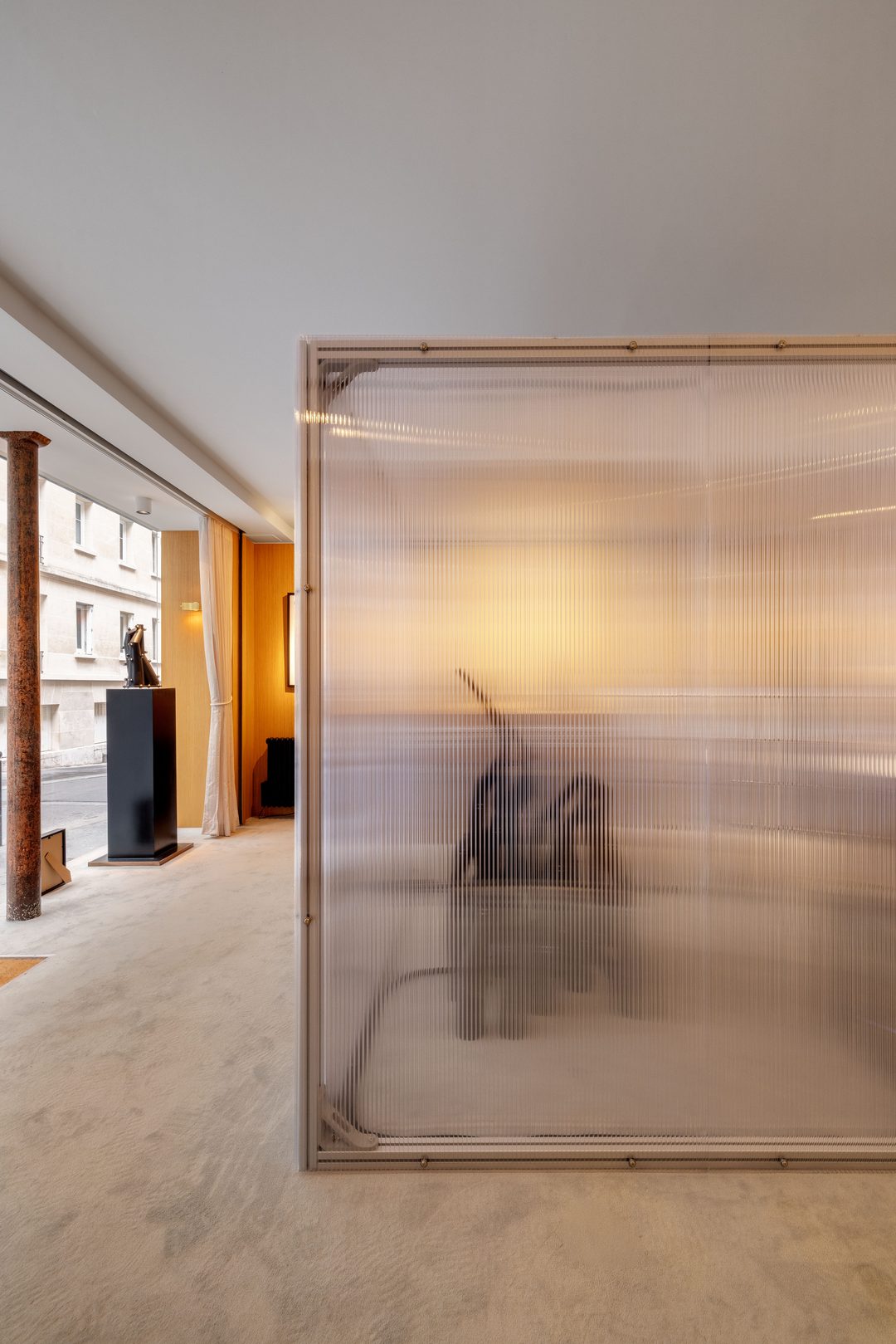 The polycarbonate cube installed in the gallery, a figure seated inside
