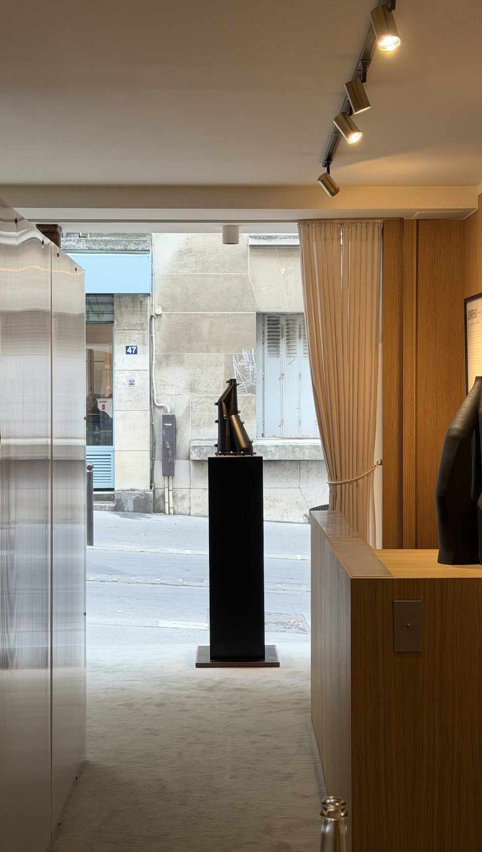 A Vorace on a black pedestal, the street visible through the gallery window